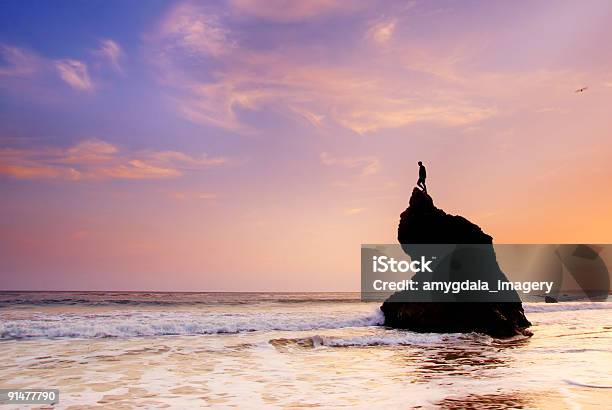 Photo libre de droit de Ciel Coucher De Soleil Sur Locéan Et Homme Au Sommet De La Formation Rocheuse banque d'images et plus d'images libres de droit de Coucher de soleil