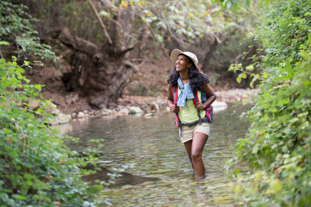 Backpacker woman  wading in river in the forest.