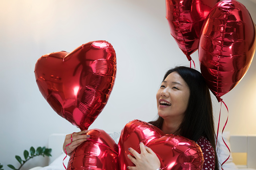 Young Chinese woman with red heart shaped balloons