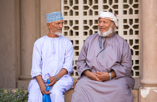 Nizwa, Oman -June 24th, 2017: two old omani men in traditional clothing, socialising at a Friday street market in old part of the town