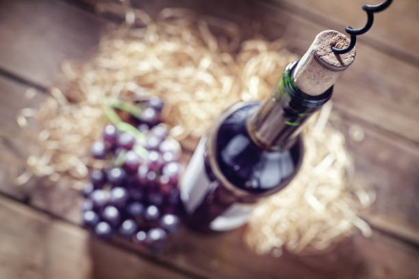 Bottle of wine, cork and corkscrew on wooden table Bottle of wine, grapes, cork and corkscrew on wooden table uncork wine stock pictures, royalty-free photos & images