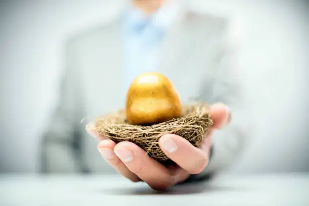 Photo of Retirement savings golden nest egg in businessman hand