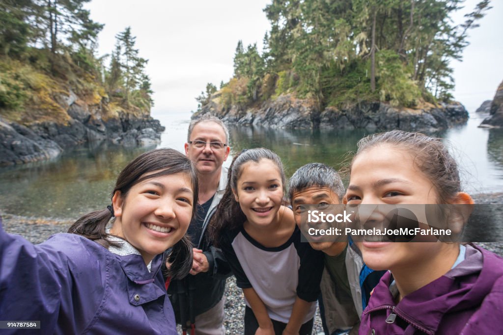 Multi-Ethnic randonnée famille posant pour Selfie sur la plage sauvage robuste - Photo de Famille libre de droits