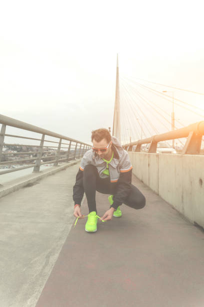 istock Male jogger tying shoelace on a big bridge. 914789086