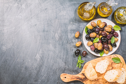 Olive oil, different olive fruites and fresh bread. Top view Testing fresh mediterranean extra virgin olive oil.