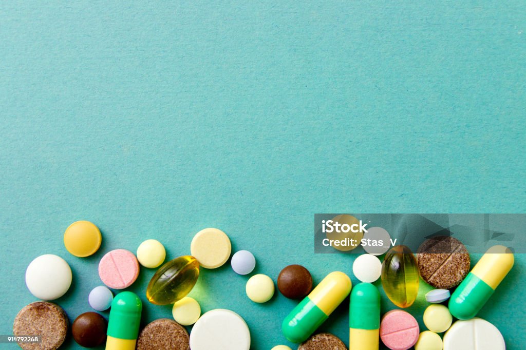 Molte pillole colorate su sfondo rosso con spazio di copia. Modello , Identificazione delle pillole - Foto stock royalty-free di Integratore vitaminico