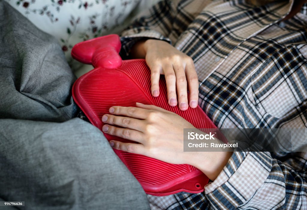 Mujer caucásica de tener período doloroso calambres - Foto de stock de Bolsa de agua caliente libre de derechos