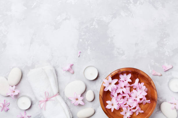 istock Spa, aromatherapy, beauty background with massage pebble, perfumed flowers water and candles on stone table top view. 914797322