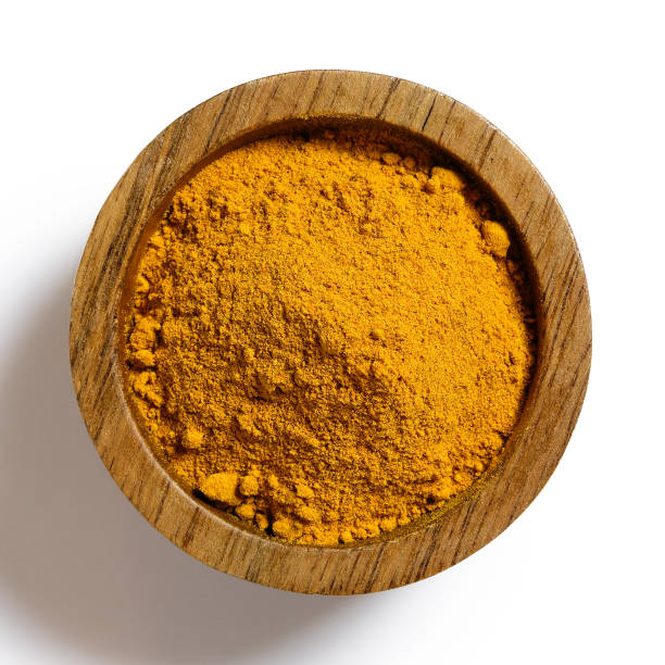 Turmeric powder in dark wood bowl isolated on white from above. Turmeric powder in dark wood bowl isolated on white from above. saffron stock pictures, royalty-free photos & images