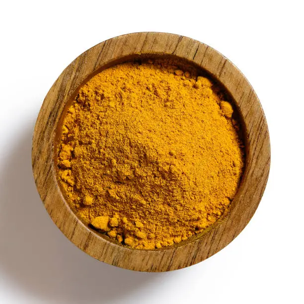 Turmeric powder in dark wood bowl isolated on white from above.