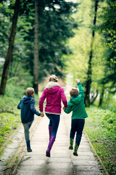 It's finally Spring! Three kids are running on city park path.\n