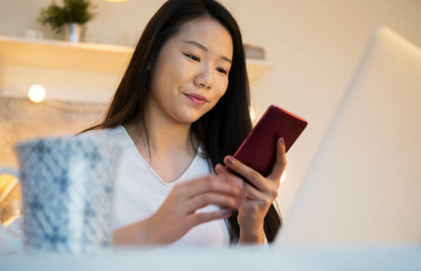 istock Young Chinese woman working on laptop at kitchen 914806692