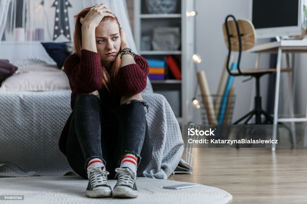 Worried girl holding head Worried, young girl holding her head and looking away in her bedroom Teenager Stock Photo