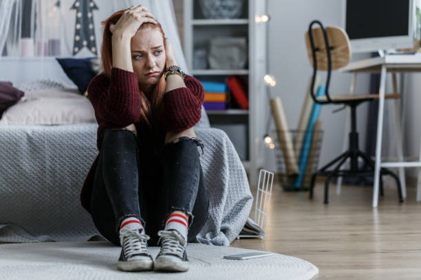 Worried girl holding head Worried, young girl holding her head and looking away in her bedroom depression sadness stock pictures, royalty-free photos & images