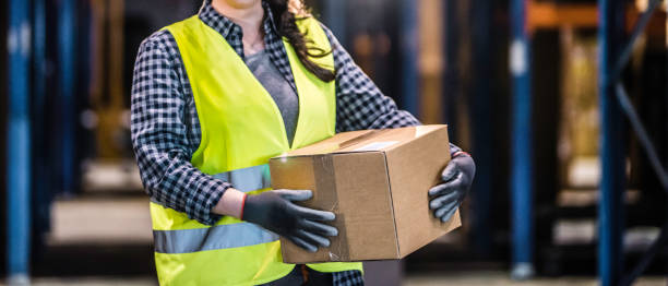 istock Female warehouse worker holding cardboard box 914813468