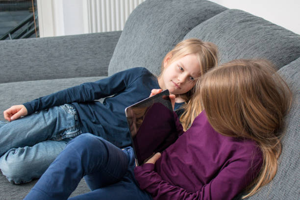 istock Girl hides screen from younger sister 914814032