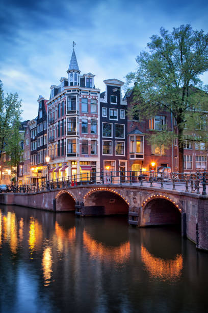 Evening in Amsterdam Amsterdam city in the evening, old houses and bridge on canal, corner of Grimburgwal and Oudezijds Voorburgwal, North Holland, Netherlands, Europe canal house photos stock pictures, royalty-free photos & images