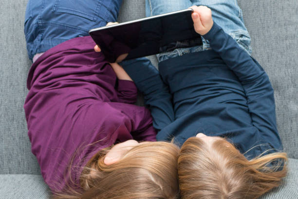 istock Top view on 2 girls who enjoy entertaining content on a tablet 914814294