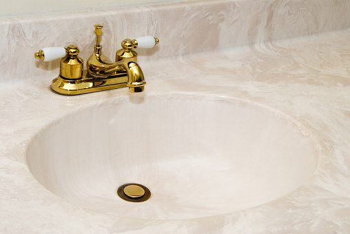 New cultured marble bathroom sink with gold finish faucet and copy space.