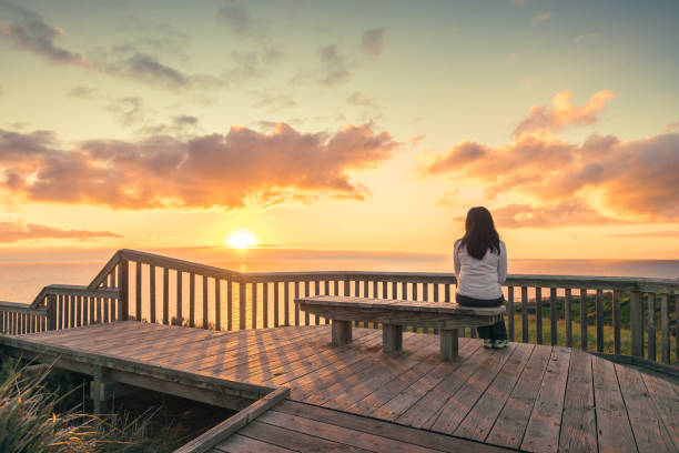 frau, die bei sonnenuntergang an hallett cove promenade - scenics pedestrian walkway footpath bench stock-fotos und bilder