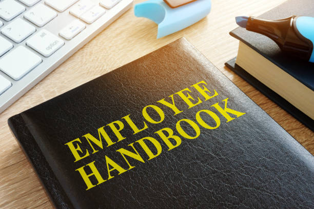 mitarbeiter-handbuch auf einem schreibtisch aus holz. - legal system business book advice stock-fotos und bilder