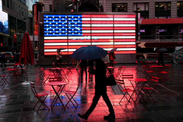 雨の中での都市: 傘で有名な旗を渡すことで歩行者のシルエット濡れているタイムズ ・ スクエア - raining cats and dogs 英語の慣用句 ストックフォトと画像