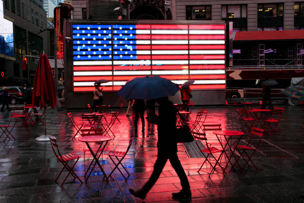 cidade na chuva: silhueta de pedestre com guarda-chuva, passando a famosa bandeira em molhar a times square - raining cats and dogs - fotografias e filmes do acervo