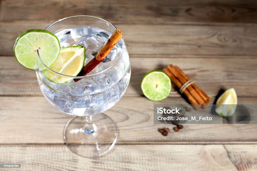 Gin tonic on wood background Gin tonic with lime slice, cinnamon sticks and peppercorns on wood background Gin Stock Photo
