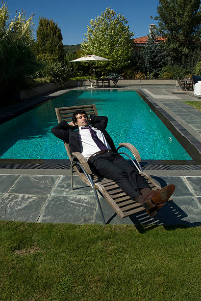 Businessman reclining in lounge chair near pool, Zekeriyak&#246;y, Istanbul, Turkey stock photo