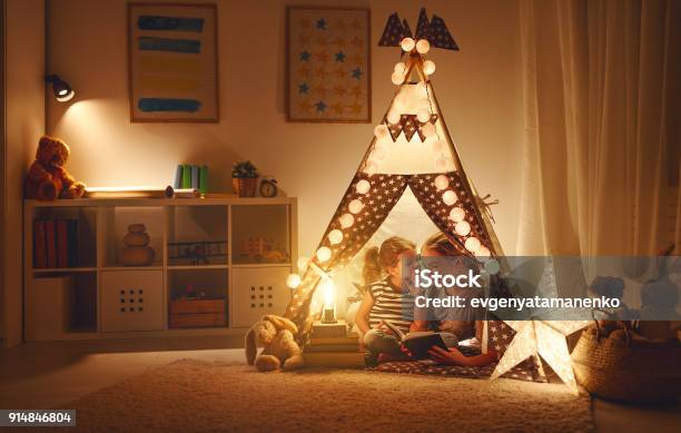 Mother And Child Daughter With A Book And A Flashlight Before Going To Bed Stock Photo - Download Image Now