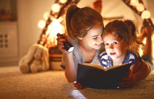 istock mother and child daughter with a book and a flashlight before going to bed 914847052