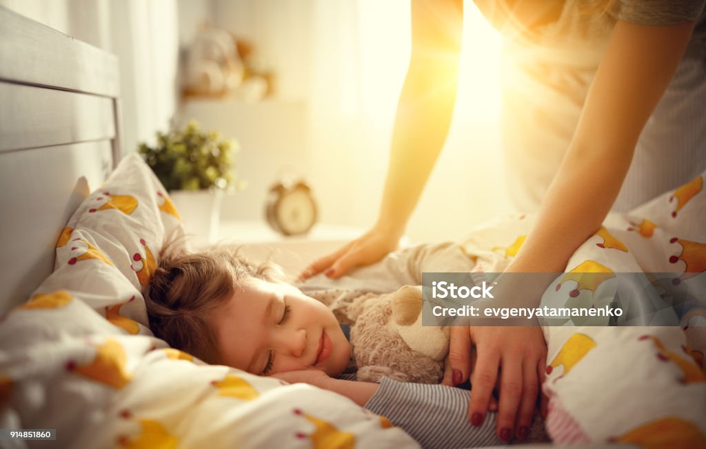 mother wakes up sleeping child daughter girl in morning mother wakes up sleeping child daughter girl in the morning Child Stock Photo