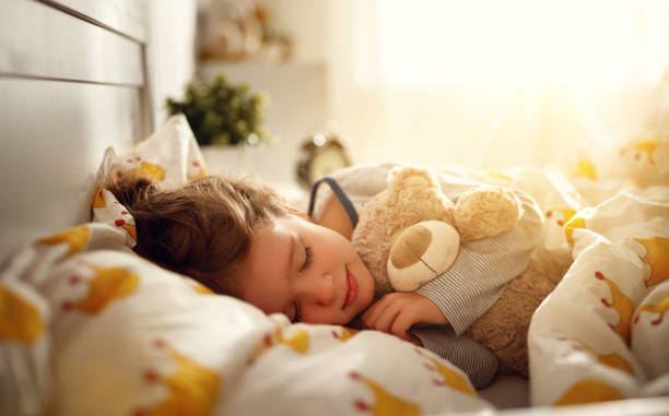 bambina dorme nel suo letto con orsacchiotto giocattolo al mattino - dreams child sleeping little girls foto e immagini stock