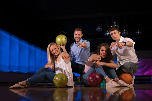 happy young couples with bowling balls sitting together smiling at camera havin fun