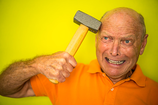 senior man with hammer on his head - concept shot for pain, headache, chronic illness - color surge theme on bright green background