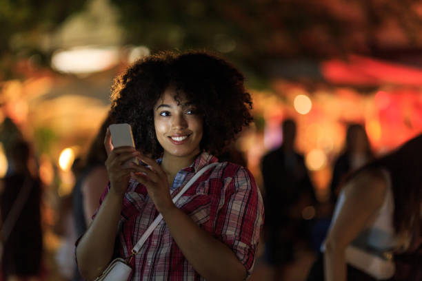 istock Smiling woman using smart phone at night on street 914864264