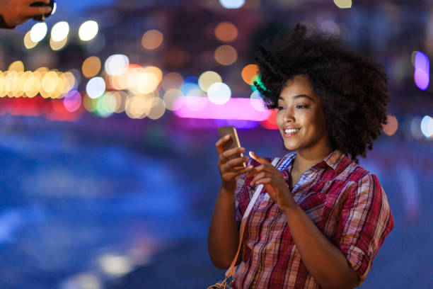 istock Smiling woman using smart phone at night on street 914864276
