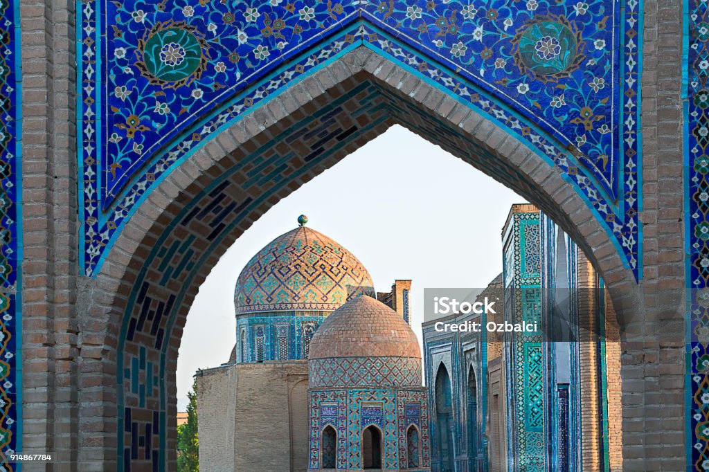 View over the mausoleums and domes of the historical cemetery of Shahi Zinda through an arched gate, Samarkand, Uzbekistan. Historical cemetery of Shahi Zinda, Samarkand, Uzbekistan Uzbekistan Stock Photo