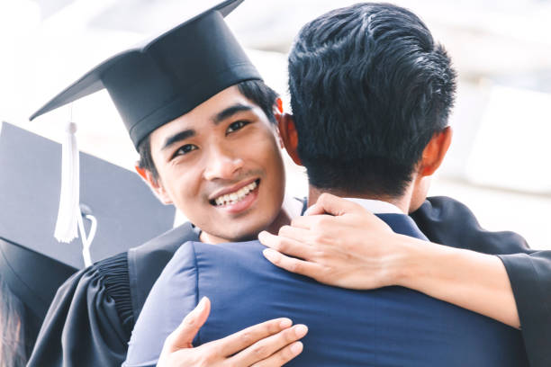 istock Students celebrating successful graduation hugging with friend 914870904