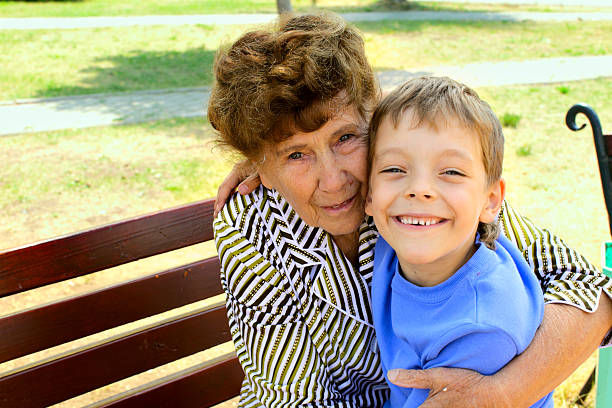 proud grandma pinching her annoyed grandson in his cheek. 