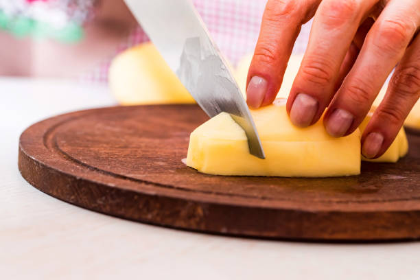 istock Female hands cut potatoes on wooden board 914876710