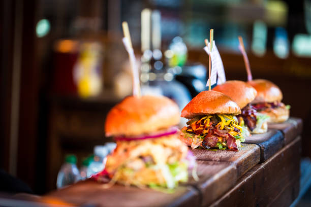 крупным планом свежего пламени жареные гамбургеры отображается в ряд на продовольственном рынке - street food фотографии стоковые фото и изображения