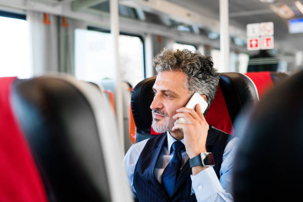 istock Mature businessman with smartphone travelling by train. 914892478