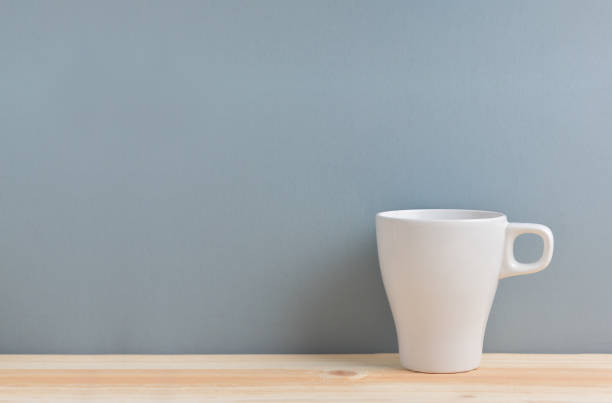 istock White cup of coffee on blue background. 914894824