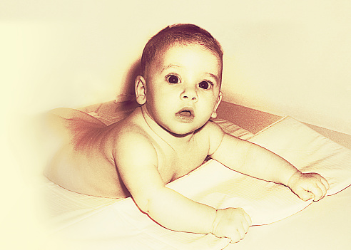 vintage sepia toned photo from the sixties/seventies of a naked baby  looking at camera