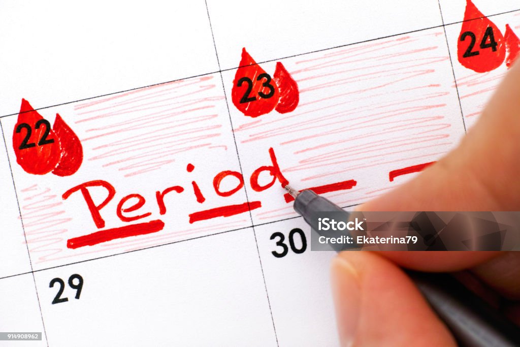 Woman fingers with pen writing reminder Period in calendar. Woman fingers with pen writing reminder Period in calendar. Close-up. Menstruation Stock Photo