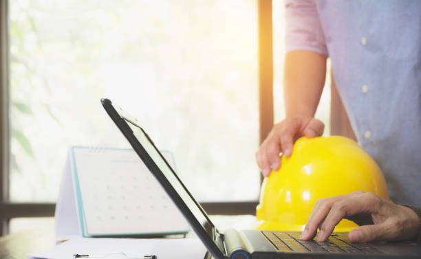 istock Architect engineer using laptop for working with yellow helmet on desk. 914912900