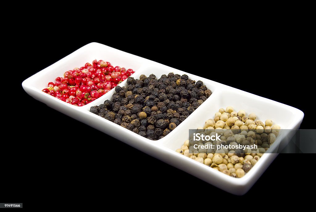 Rosa, blanco y negro peppercorns en un plato blanco - Foto de stock de Alimento libre de derechos