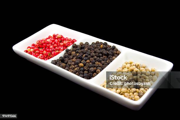 Rosa Blanco Y Negro Peppercorns En Un Plato Blanco Foto de stock y más banco de imágenes de Alimento