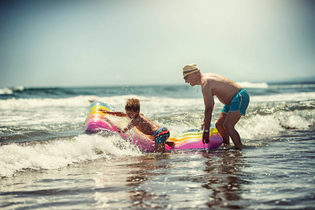istock Senior man playing with grandson in sea waves 914920740